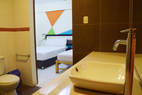 a bathroom with a sink and a room with two beds at Hotel Colors Canada in Lima