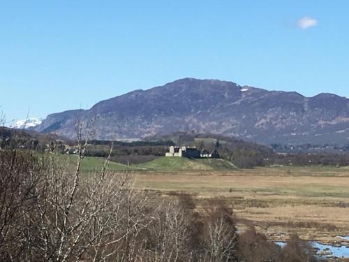 a house in a field with mountains in the background at Netherwood House in Newtonmore