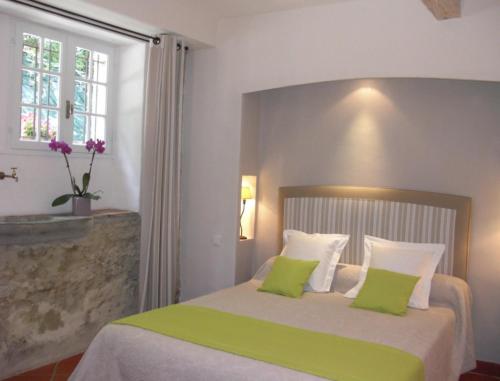 a bedroom with a bed with green and white pillows at Chambres d'Hotes Domaine de la Capelle in Saint-Martin-Lalande