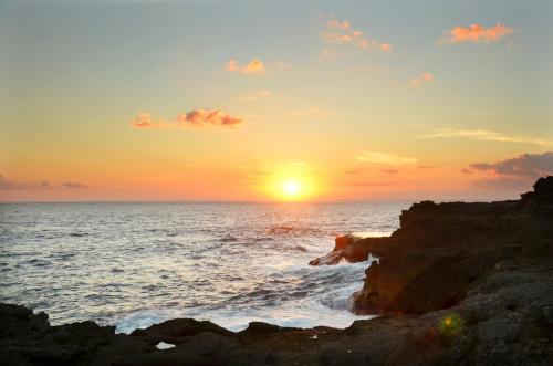a sunset over the ocean with a rocky beach at Sedok Jineng Villa Lembongan in Nusa Lembongan