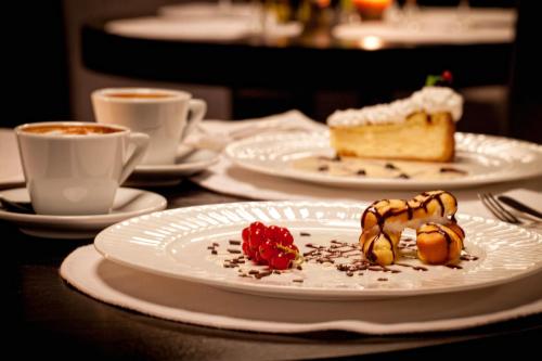a table with plates of desserts and cups of coffee at Voyage Hotel in Karagandy
