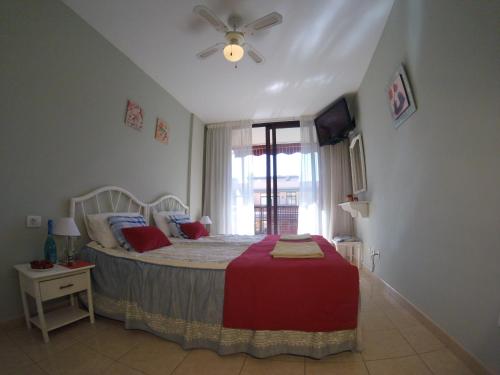 a bedroom with a bed with a ceiling fan and a window at Olivia Sunset Playa in Puerto de Santiago