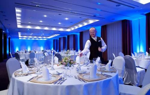 a man standing in front of a table in a banquet hall at Dorint Am Goethepark Weimar in Weimar