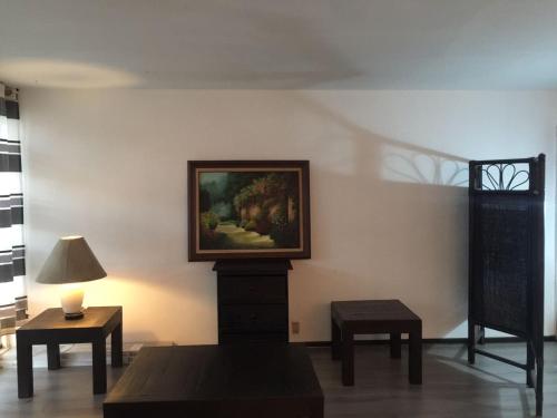 um quarto com uma pintura na parede e duas mesas em CDMX - Great Location at Napoles em Cidade do México