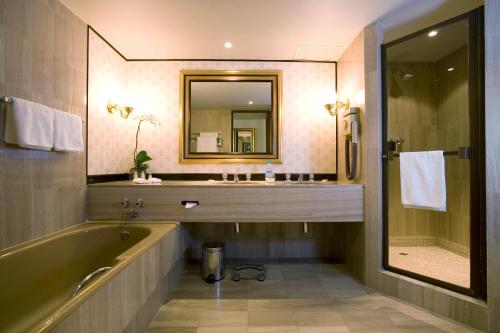 a bathroom with a tub and a sink and a mirror at Southern Sun Cape Sun in Cape Town
