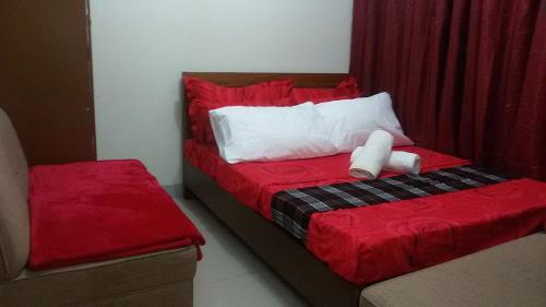a bedroom with a bed with red sheets and white pillows at Nica's Place Property Management Services at Horizons 101 Condominium in Cebu City