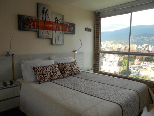 1 dormitorio con cama y ventana grande en All Inclusive Suites, en Medellín