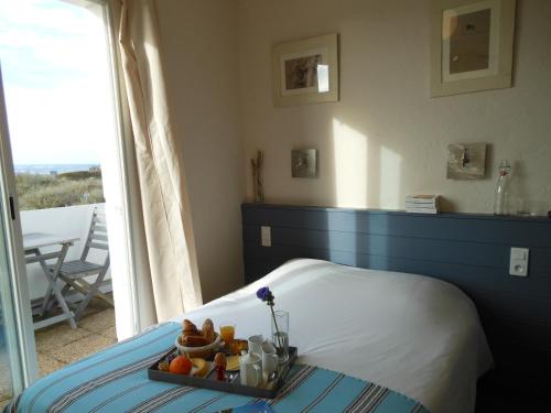 ein Schlafzimmer mit einem Bett und einem Tablett mit Obst darauf in der Unterkunft Hôtel de la Petite Plage in Saint-Georges-dʼOléron