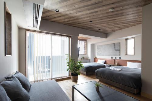 a bedroom with two beds and a living room with a couch at Hotel Vintage Tokyo in Tokyo