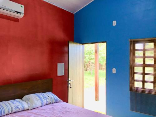een slaapkamer met rode en blauwe muren en een bed bij Chalé Quintal Amazon in Macapá