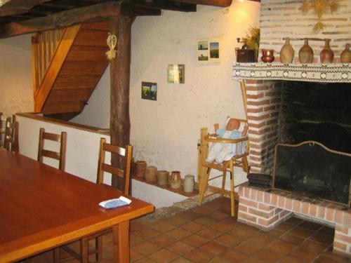 uma sala de estar com lareira e uma mesa e cadeiras em Ferme Peschard em Séris