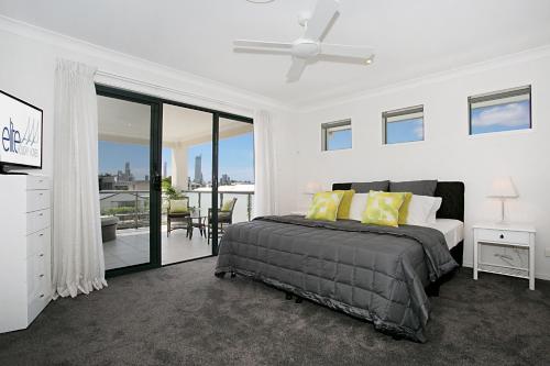 a white bedroom with a bed and a balcony at Escape to the Coast in Gold Coast
