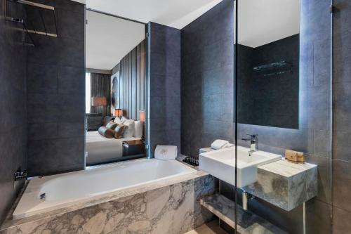 a bathroom with a tub and a sink and a bed at The Beetson Hotel in Brisbane