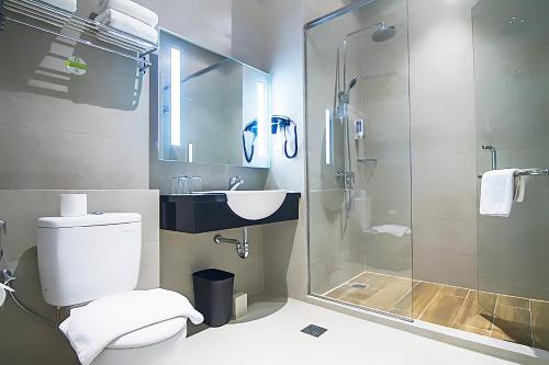 uma casa de banho com um chuveiro, um WC e um lavatório. em Zest Sukajadi Bandung by Swiss-Belhotel International em Bandung