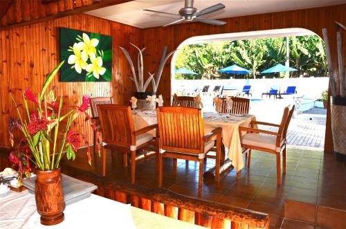 a dining room with a table and chairs and a patio at Britannia Hotel in Grand'Anse Praslin