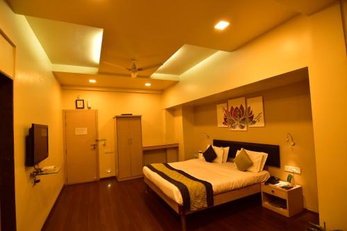 a hotel room with a bed and a tv at MY Bizz Hotel Sapna in Pune