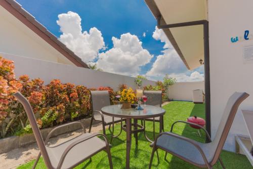 a patio with a table and chairs on the grass at Chalong - 2 Bedroom Hideaway Private Pool Villa - Phuket in Chalong 