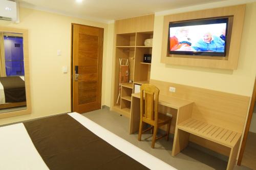 a room with a desk and a television on the wall at Águila Dorada Selva Hotel in Pucallpa