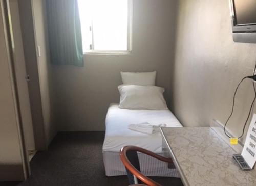 a small room with a bed and a window at Commercial Hotel Motel Lithgow in Lithgow
