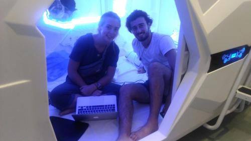two men sitting on a bed with a laptop at Space Cap Hotel in Kota Kinabalu