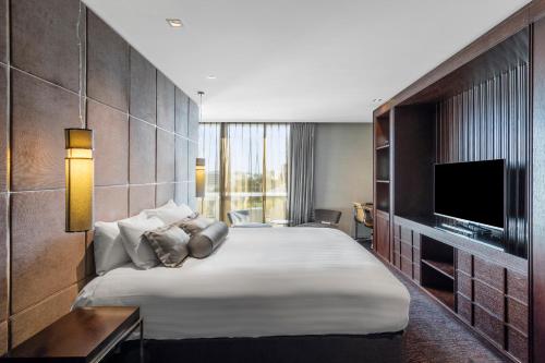 a hotel room with a large bed and a television at Gambaro Hotel Brisbane in Brisbane