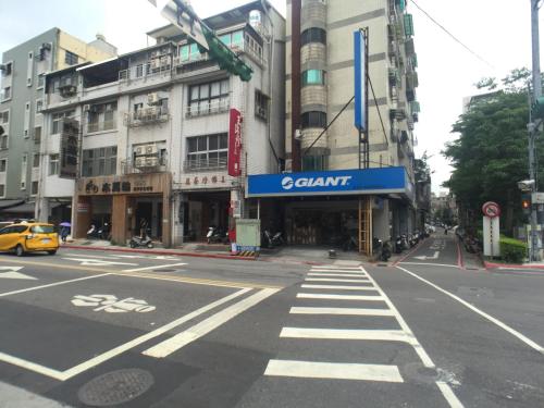 an empty city street with a yellow car and buildings at 耘荷居 Yún Inn in Taipei