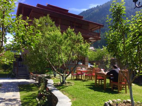 a man sitting at a table in front of a building at Shivadya - A Luxury Boutique Experience in Manāli