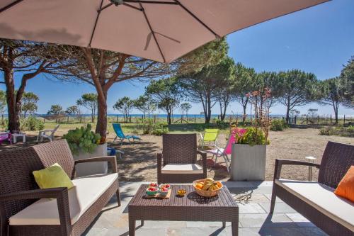 un patio avec des chaises, une table et un parasol dans l'établissement MAISONS BORD DE MER- MARINE DE SORBO - Gîtes 3 épis, à Pinarellu