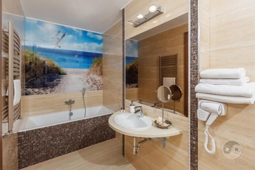 La salle de bains est pourvue d'un lavabo et d'une baignoire. dans l'établissement Hotel SPA Activia, à Jastrzębia Góra