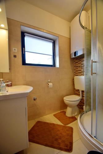 a bathroom with a toilet and a sink and a window at Haus Tanja in Malinska