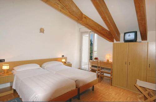 una camera con un letto e una televisione di Villa Flora a Levico Terme
