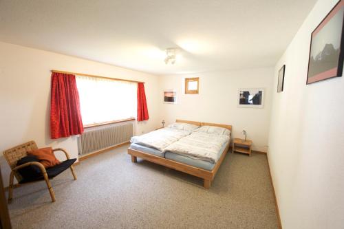 um quarto com uma cama, uma janela e uma cadeira em Ferienhaus Wanner em Splügen