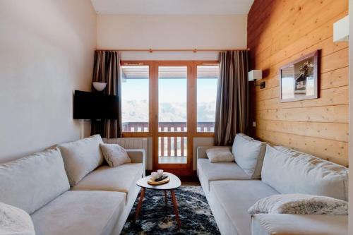 a living room with a couch and a table at Residence La Marelle et Le Rami - maeva Home in Les Coches