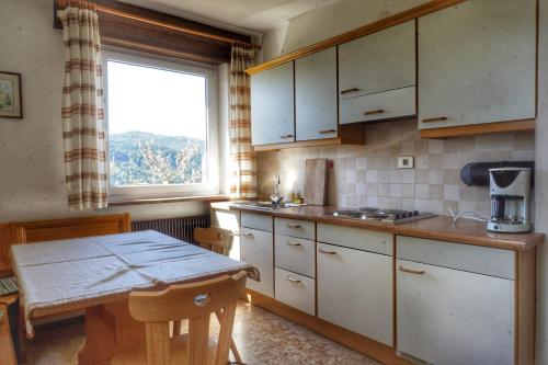 a kitchen with white cabinets and a table and a window at Haus Elli in Nova Ponente