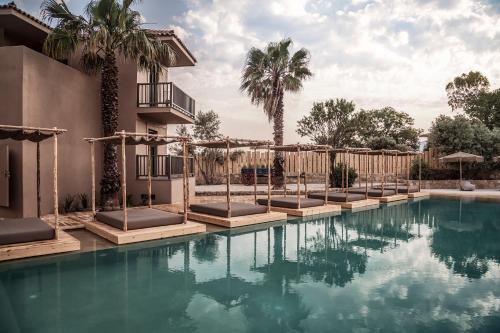 a pool with chaise lounges next to a building at Doryssa Boutique Hotel in Pythagoreio