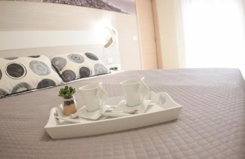 a white tray with cups and saucers on a bed at A'MANTIA HOTEL in Amantea