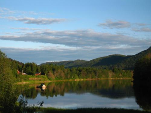 a boat on a lake with mountains in the background at Klarälvens Camping in Stöllet