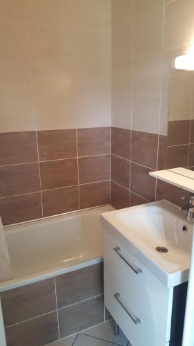 een badkamer met een witte wastafel, een bad en een wastafel bij Chez Fifille appartement dans Honfleur parking privé in Honfleur