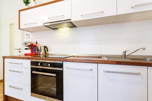 a white kitchen with a sink and a stove at Golden Apartments Rezidence Nová Karolina in Ostrava