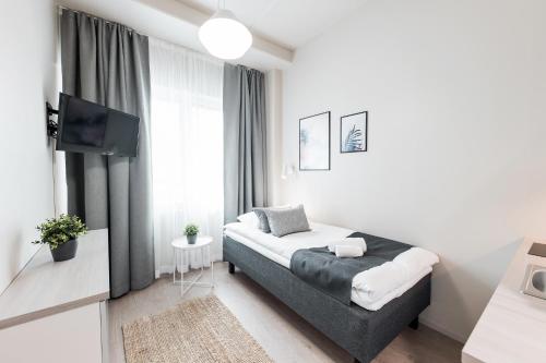 a white bedroom with a bed and a tv at Forenom Aparthotel Vantaa Tikkurila in Vantaa