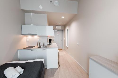 a kitchen with white cabinets and a couch in a room at Forenom Aparthotel Vantaa Tikkurila in Vantaa