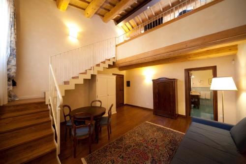 a living room with a staircase and a table and chairs at Antico Casale Bergamini in SantʼAmbrogio di Valpolicella