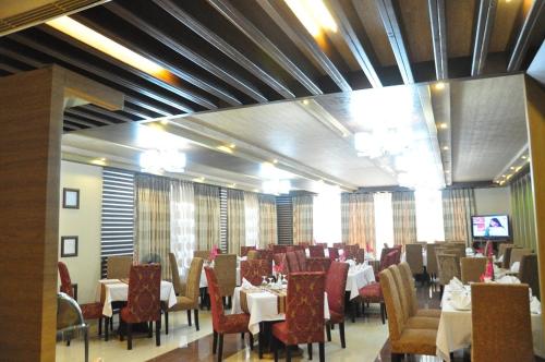 a dining room with tables and chairs and a television at Marino Hotel - Best near Airport in Dhaka