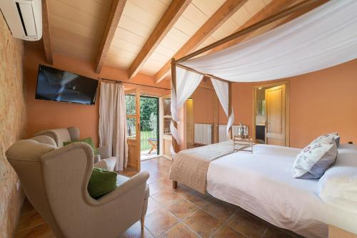 a bedroom with a bed and a chair in a room at Finca - Agroturisme Sa Parellada in Binibona