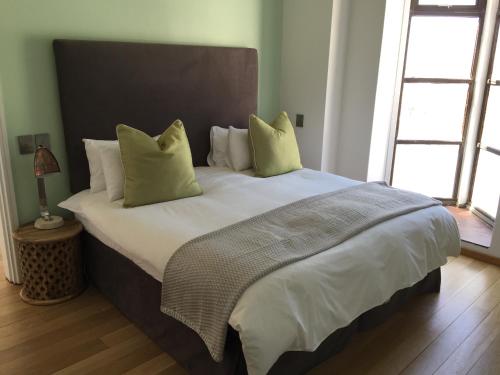 a bedroom with a large bed with green pillows at 2 Bedroom Louise in Mutual Heights in Cape Town