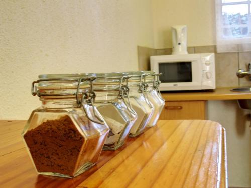 a group of four glass jars sitting on a table at Alte Welkom Guesthouse in Klerksdorp