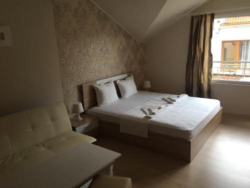 a bedroom with a bed and a chair and a window at Guest House Gloria in Nesebar