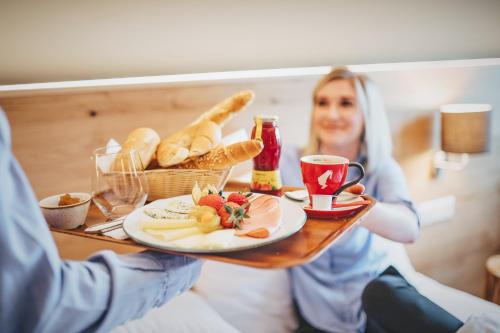 a woman holding a table with a plate of food at Hotel z'Leithen in Weng im Innkreis