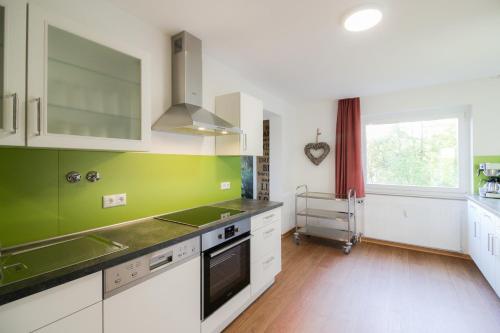 a kitchen with white cabinets and green walls at HARZ HOTEL und Gästehaus am Bornweg in Bad Sachsa