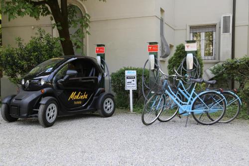 a small car with bikes parked next to a building at Mokinba Hotels Montebianco in Milan